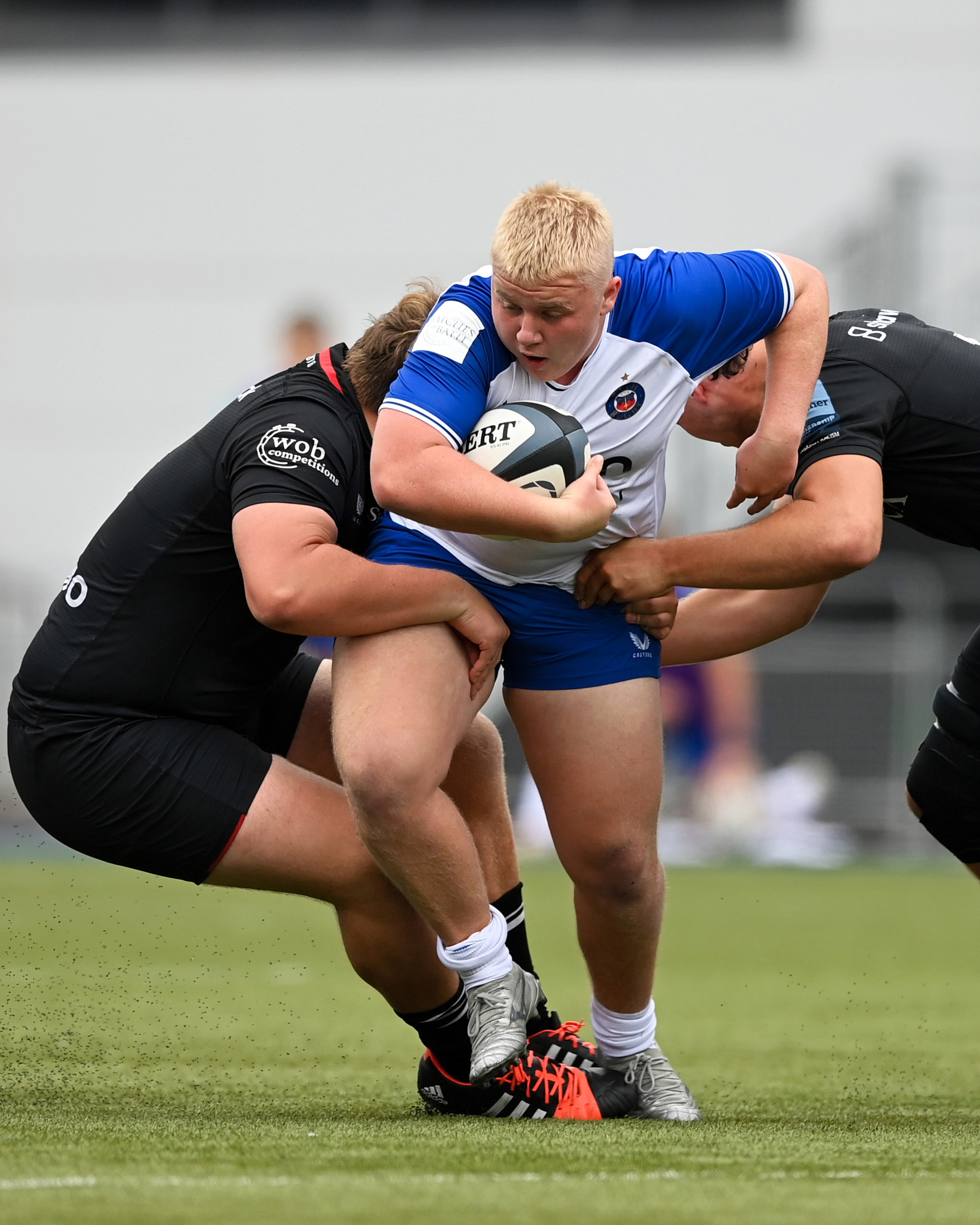 Freddie Beasley driving through two Saracens tacklers